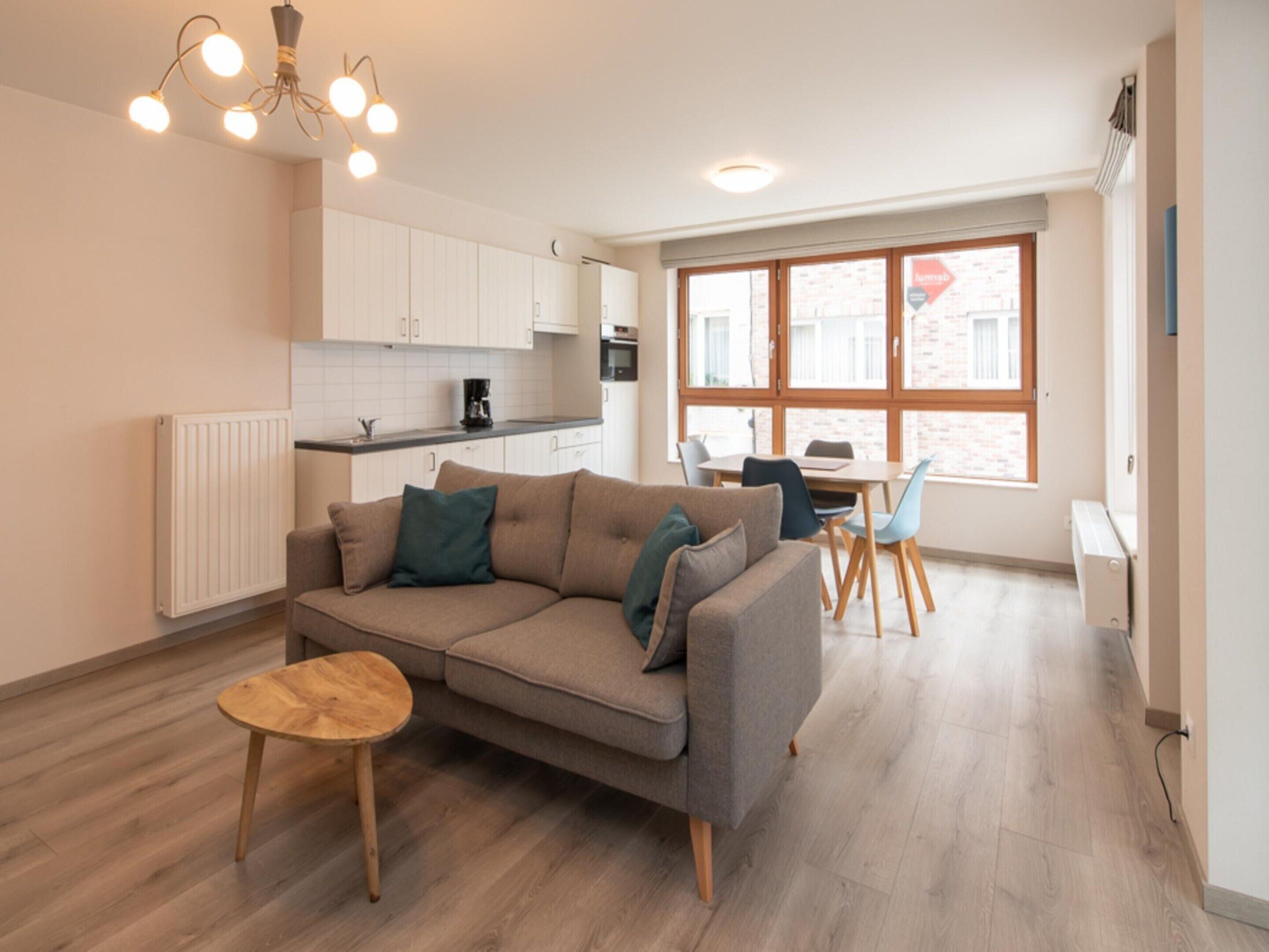 A modern apartment with a living area, kitchenette, and dining space.