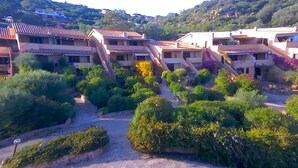 A hillside residential area with terraced houses, lush greenery, and a clear sky. - Apartment in Porto Istana Near the Beach (Olbia)