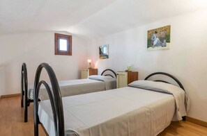 A room with two beds, a small window, and a painting on the wall. - Apartment in Porto Istana Near the Beach (Olbia)