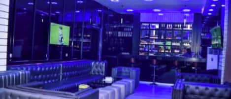 Una zona de bar con asientos y una pantalla de televisión.