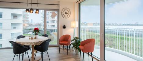 A modern living room with a large window, a round table, and two chairs.