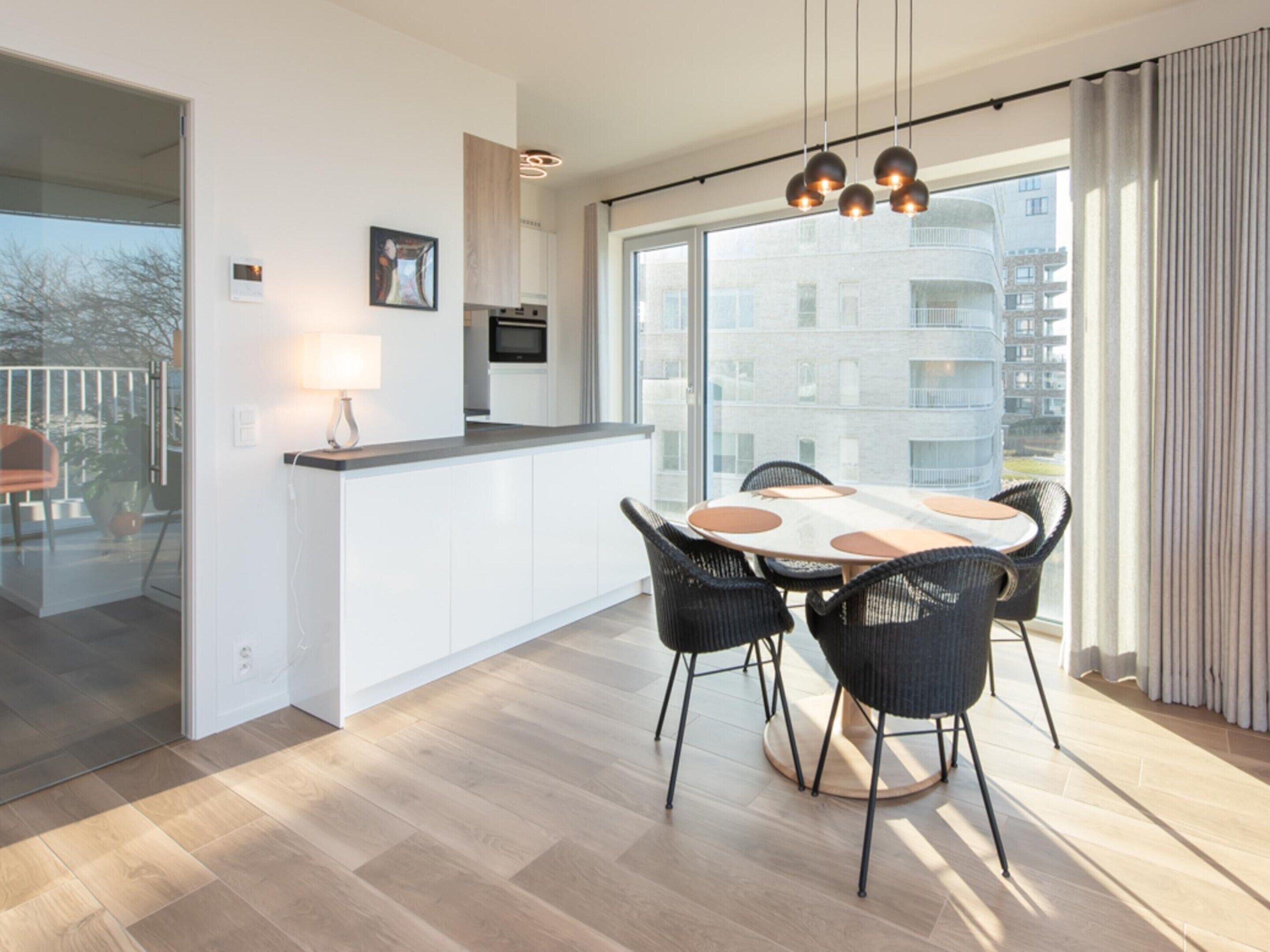 A modern apartment with a kitchen, dining area, and large windows offering a view of the city.