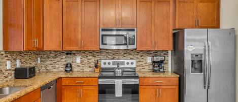 A kitchen with wooden cabinets, a stainless steel refrigerator, a microwave, a stove, and a dishwasher.