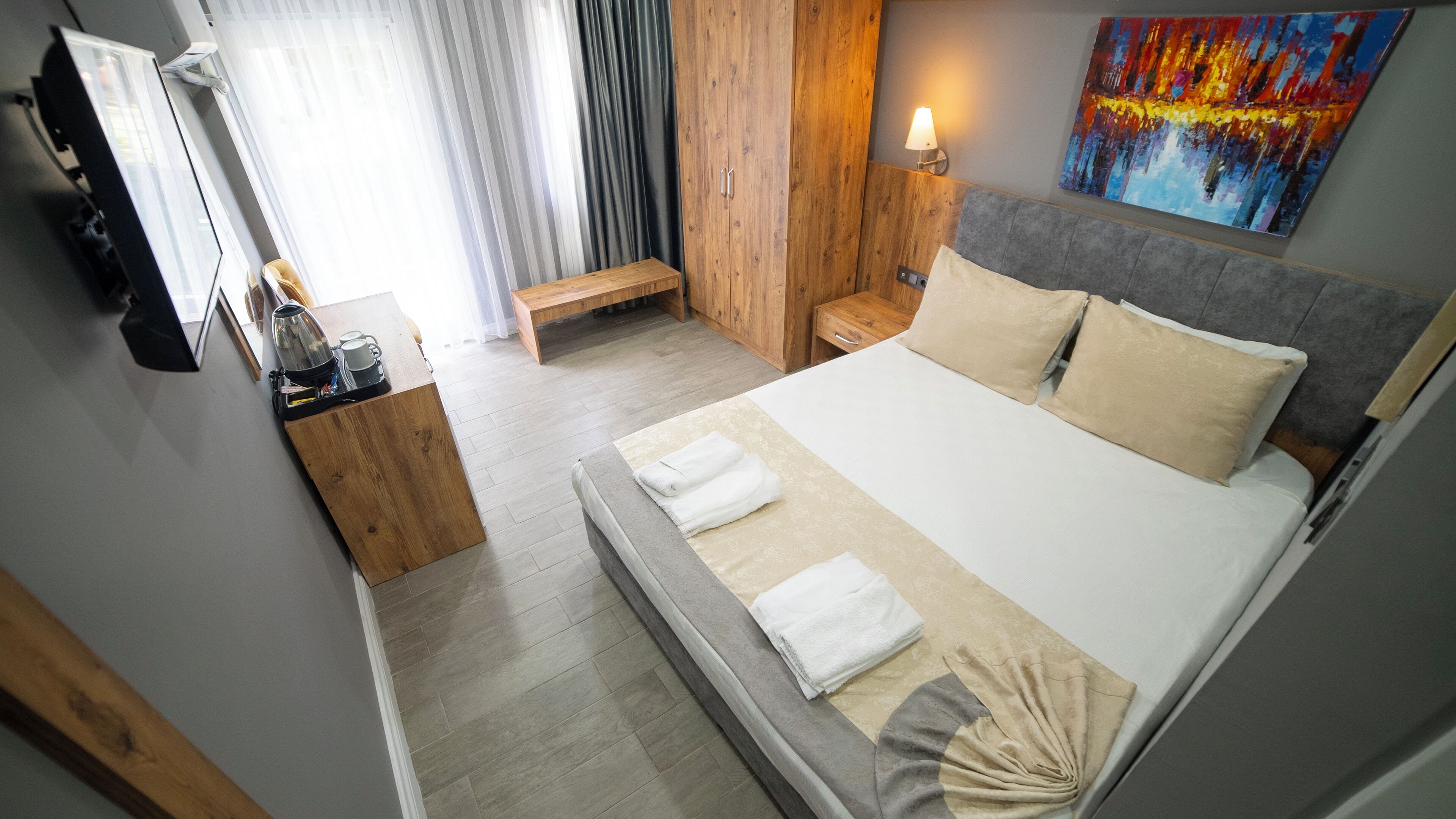 A modern hotel room with a bed, bedside table, and a painting on the wall.