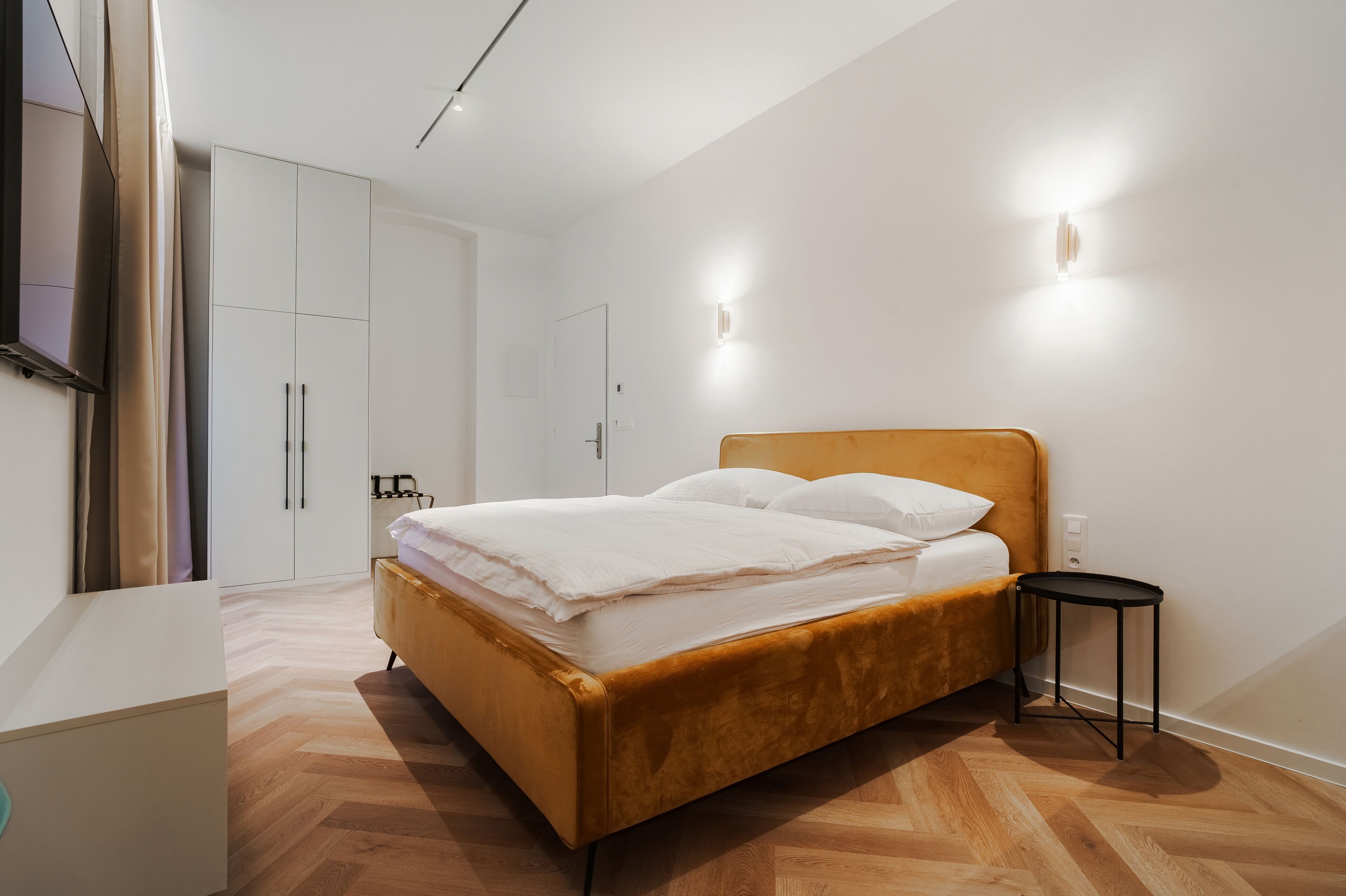 Un dormitorio con cama, mesita de noche, armario y televisor.