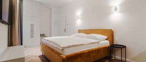 Un dormitorio con cama, mesita de noche, armario y televisor.