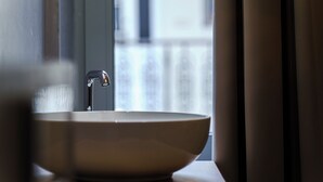 Ein Badezimmer mit einem großen, runden, beigen Waschbecken und einem modernen Wasserhahn.