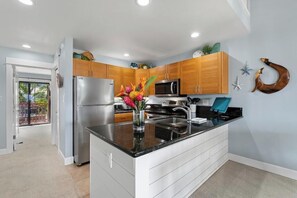 A modern kitchen with wooden cabinets, stainless steel appliances, and a black countertop.
