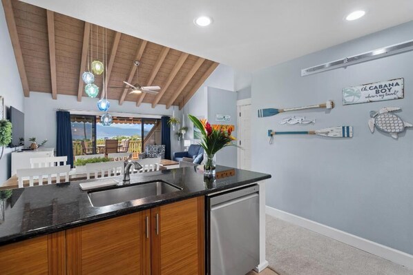 A kitchen with wooden cabinets, a black countertop, and a dishwasher.