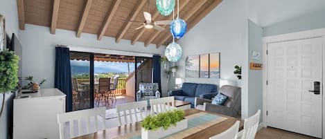 A dining area with a wooden table, white chairs, and a view of the outdoors.