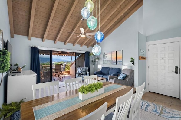 A dining area with a wooden table, white chairs, and a view of the outdoors.