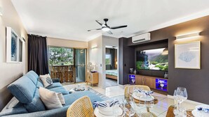 Una sala de estar moderna con un sofá, una mesa de comedor lista para seis personas y un televisor.