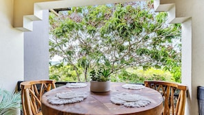 Una mesa redonda de madera con una planta en maceta en el centro, rodeada de sillas de madera.