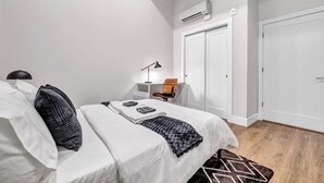 Ein Schlafzimmer mit einem Bett, einem Schreibtisch, einem Stuhl, einer Lampe und einem Kleiderschrank.