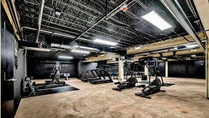 Ein geräumiges Fitnessstudio mit mehreren Laufbändern, Crosstrainern und Gewichteinrichtungen.