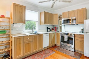 Una cucina moderna con mobili in legno, elettrodomestici in acciaio inossidabile e una finestra che permette l'ingresso di luce naturale.