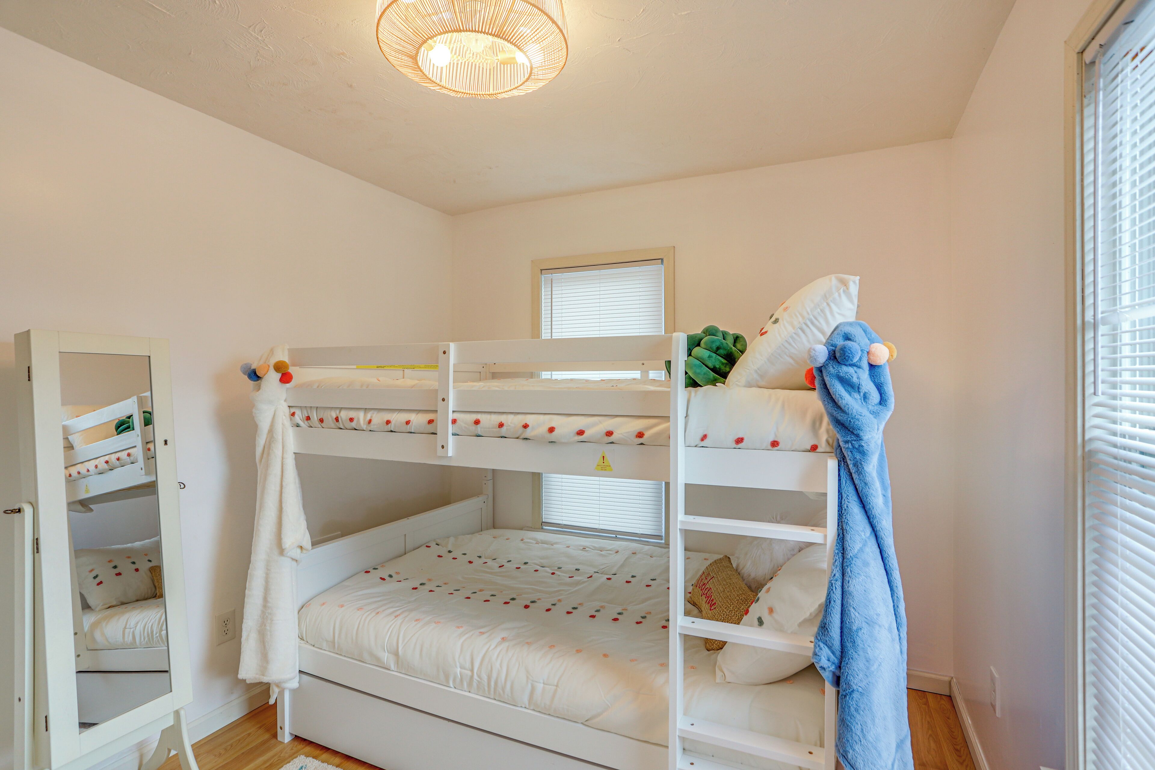 Une chambre avec un lit superposé, une fenêtre, un luminaire au plafond et une armoire.