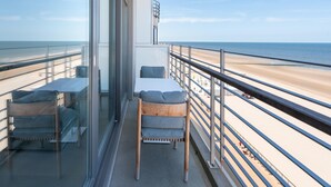 Un balcón con una mesa y sillas, con vista a la playa.