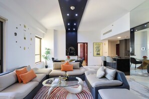 Un salon moderne comprenant un ensemble de canapés, une table basse et un coin repas avec un téléviseur.