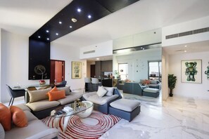 A modern living room with a sofa, coffee table, and a dining area with chairs.