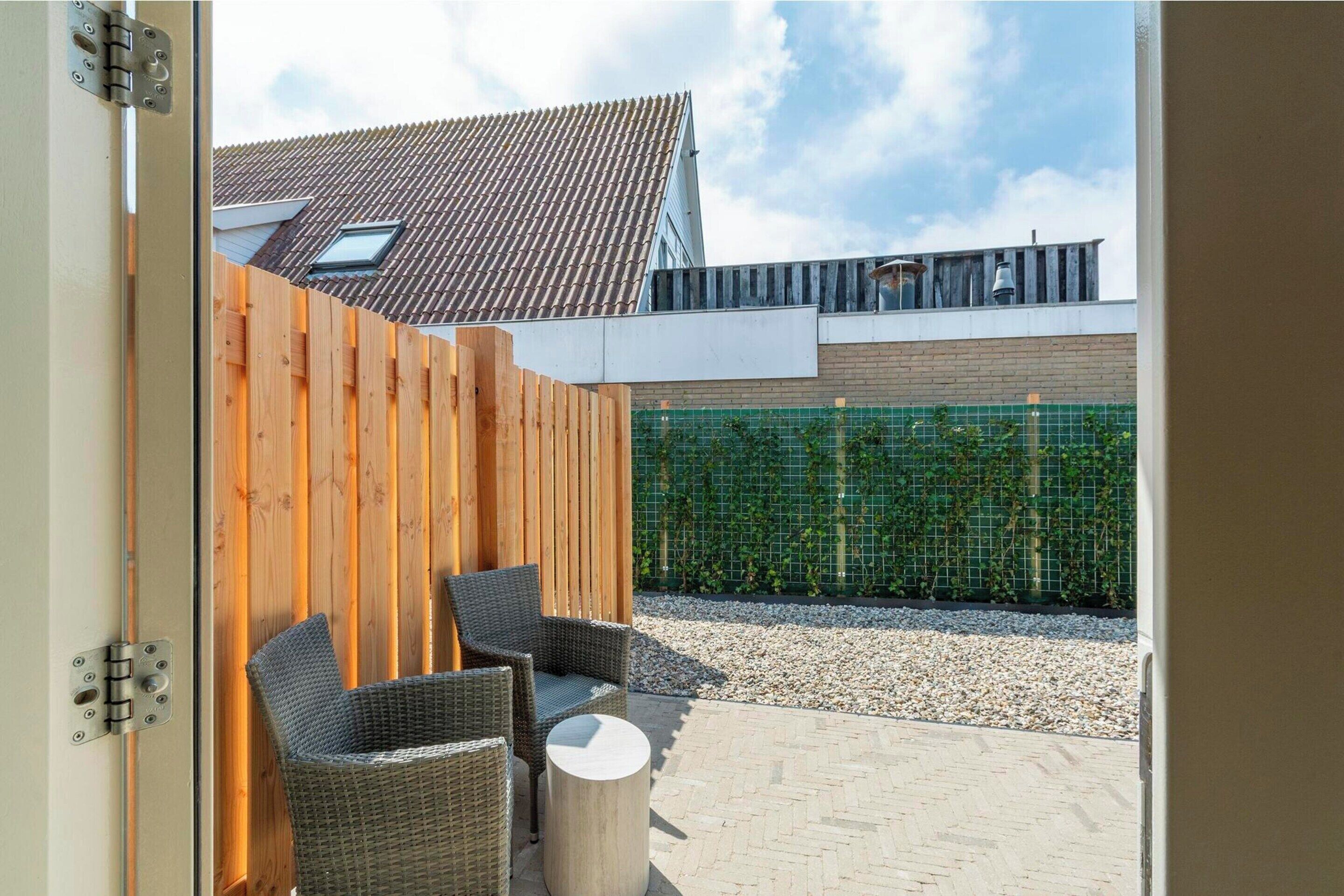 An outdoor patio with wicker furniture and a wooden fence.
