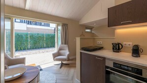 A modern kitchen with a built-in oven, a coffee maker, and a kettle on the countertop. - Beautiful Suite on the Village Square (Callantsoog)