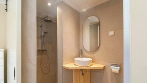 A modern bathroom with a shower, a sink, and a mirror. - Beautiful Suite on the Village Square (Callantsoog)