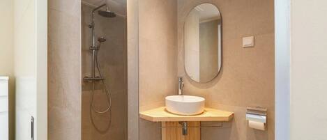 A modern bathroom with a shower, a sink, and a mirror.