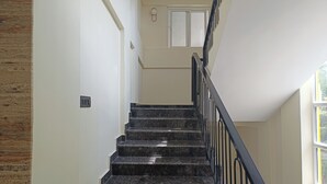 Eine Treppe mit schwarzen Geländern und Marmorstufen, die zu einer Empfangsebene mit einer Tür führt.