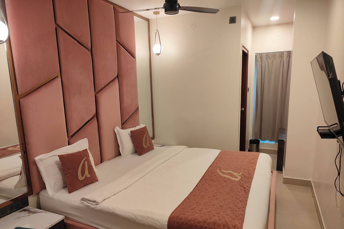A hotel room with a bed, a desk, a chair, a television, and a ceiling fan.
