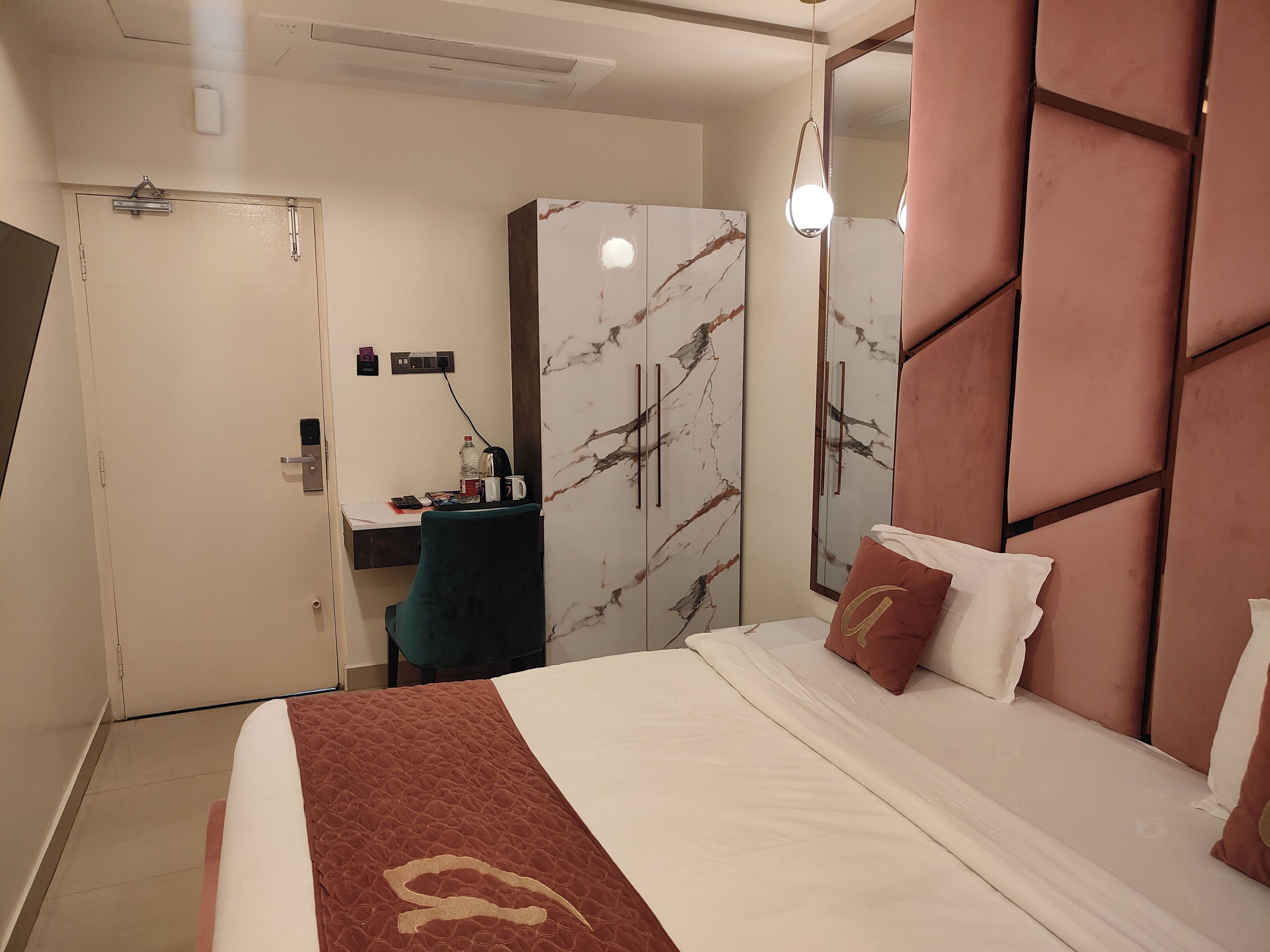 A hotel room with a bed, a desk, a wardrobe, and a mirror.