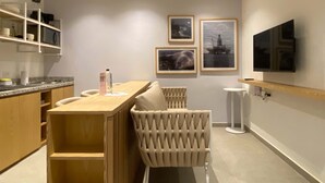 A modern kitchen with a wooden table, bar stools, and a built-in TV.