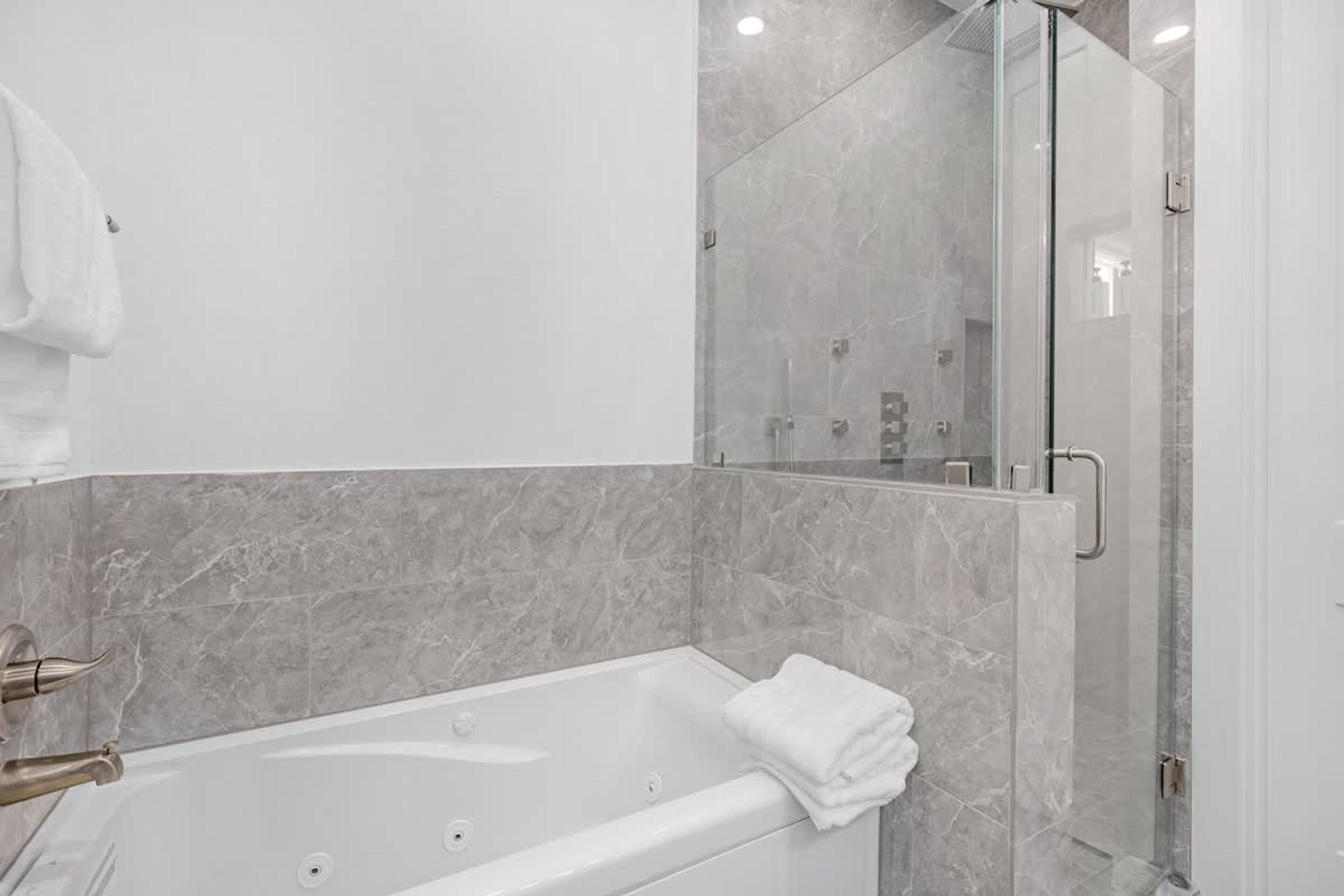 Une salle de bain moderne avec une baignoire, une douche à parois de verre et des murs en marbre.