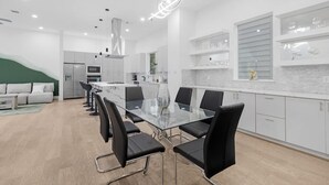 A modern kitchen with a glass dining table, black chairs, and white cabinetry. - Luxurious 3 Bed3 Bath Near Downtown Houston (Houston)