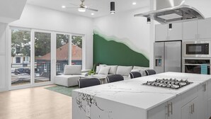 A modern kitchen with a large island, white cabinetry, and a green accent wall. - Luxurious 3 Bed3 Bath Near Downtown Houston (Houston)
