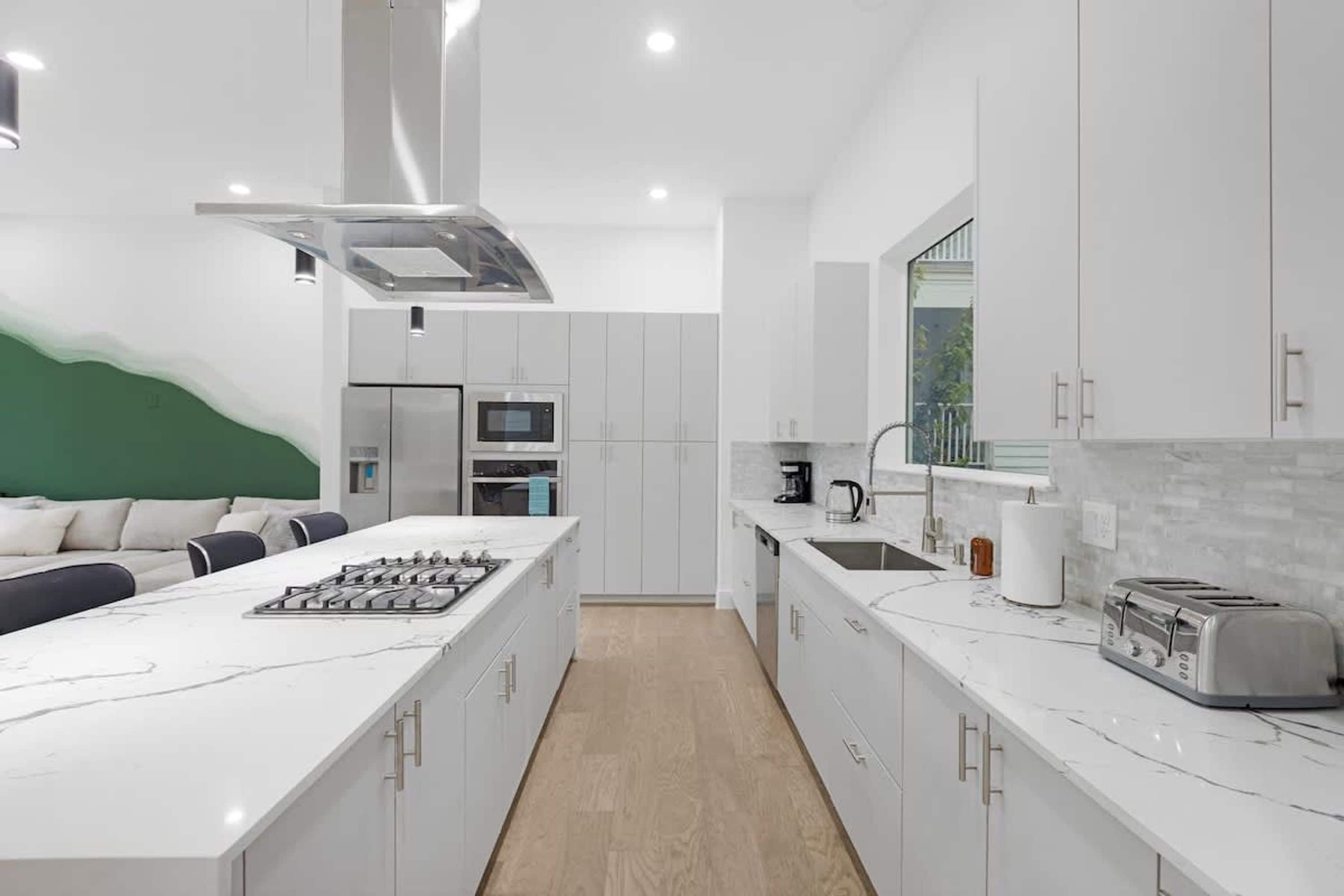 Una cocina moderna con armarios blancos, una isla central con estufa y un microondas.