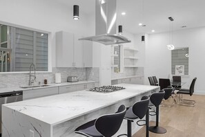 A modern kitchen with a large island, bar stools, and a dining area with a table and chairs. - Luxurious 3 Bed3 Bath Near Downtown Houston (Houston)