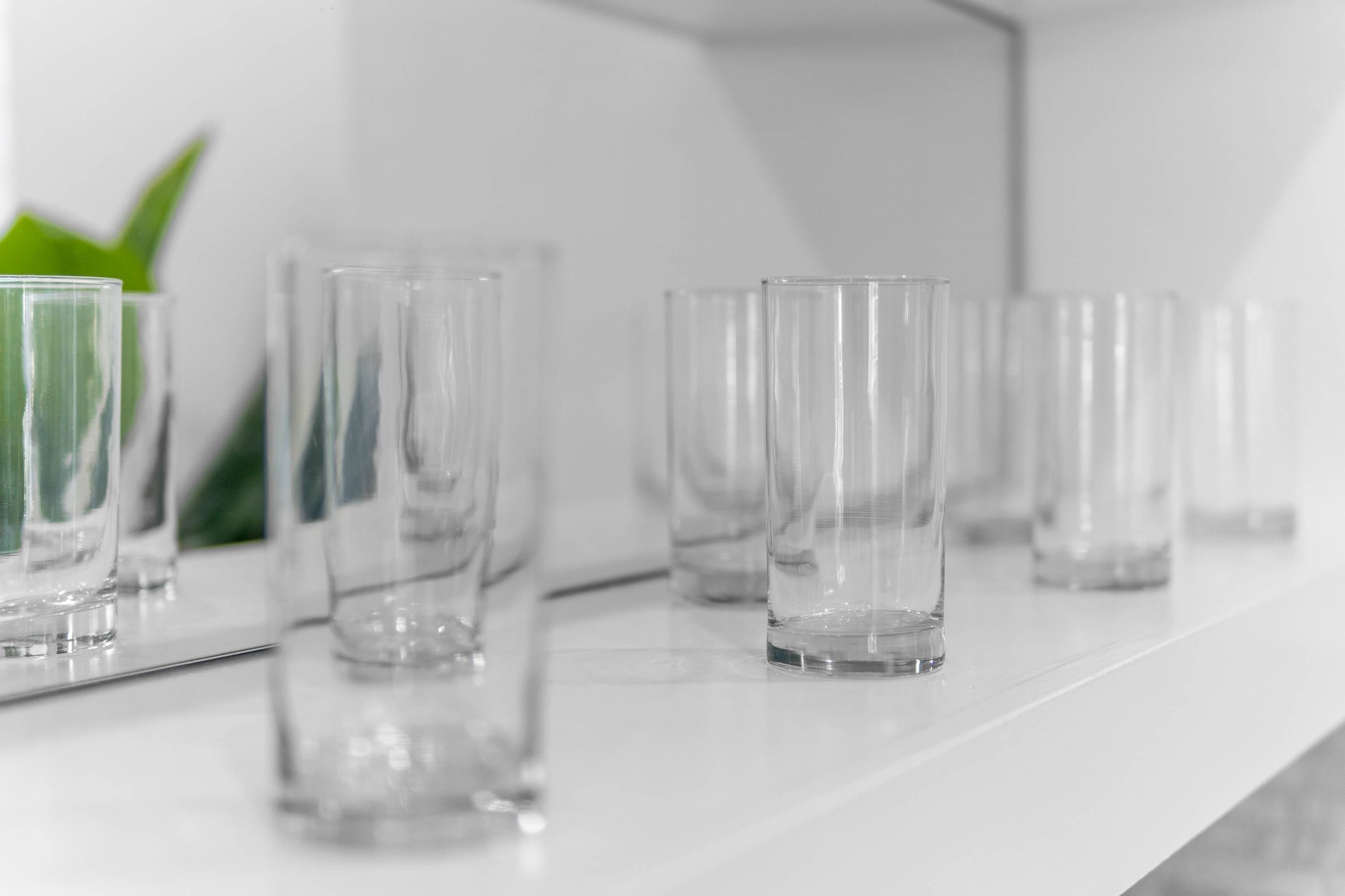 Une rangée de verres transparents et vides sur une surface blanche.