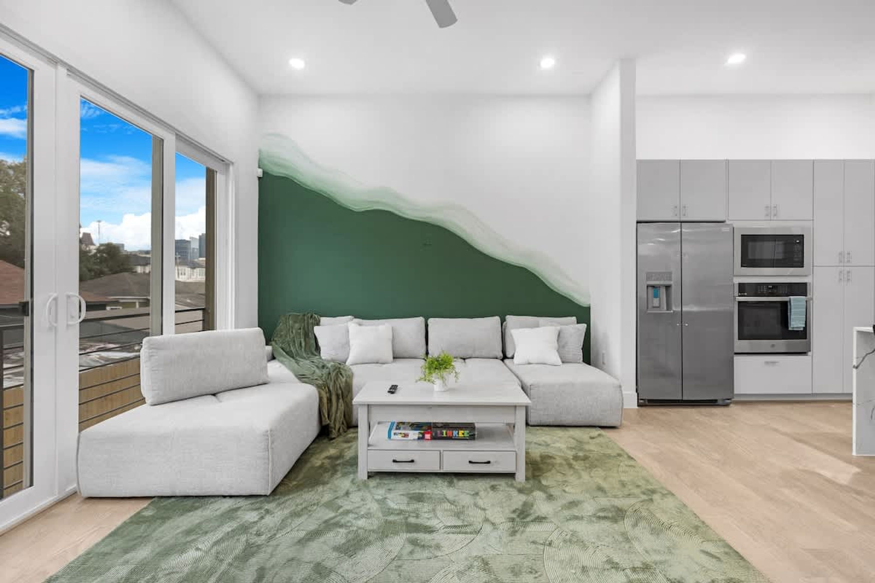 Un salon moderne avec un canapé, une table basse et un mur d’accent de couleur verte.