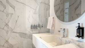 A modern bathroom with a white marble sink, a glass-enclosed shower, and a round mirror. - w Dazzling 2BR w Fantastic Terrace in CTG (Cartagena)