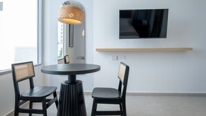 A modern room with a round table, two chairs, a mounted TV, and a wooden shelf. - w Dazzling 2BR w Fantastic Terrace in CTG (Cartagena)