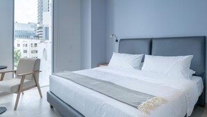 A modern bedroom with a large bed, a chair, and a view of buildings outside. - w Dazzling 2BR w Fantastic Terrace in CTG (Cartagena)