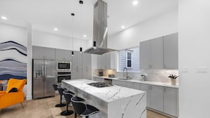 Una cocina moderna con una isla central, electrodomésticos de acero inoxidable y un amplio ventanal que proporciona luz natural.