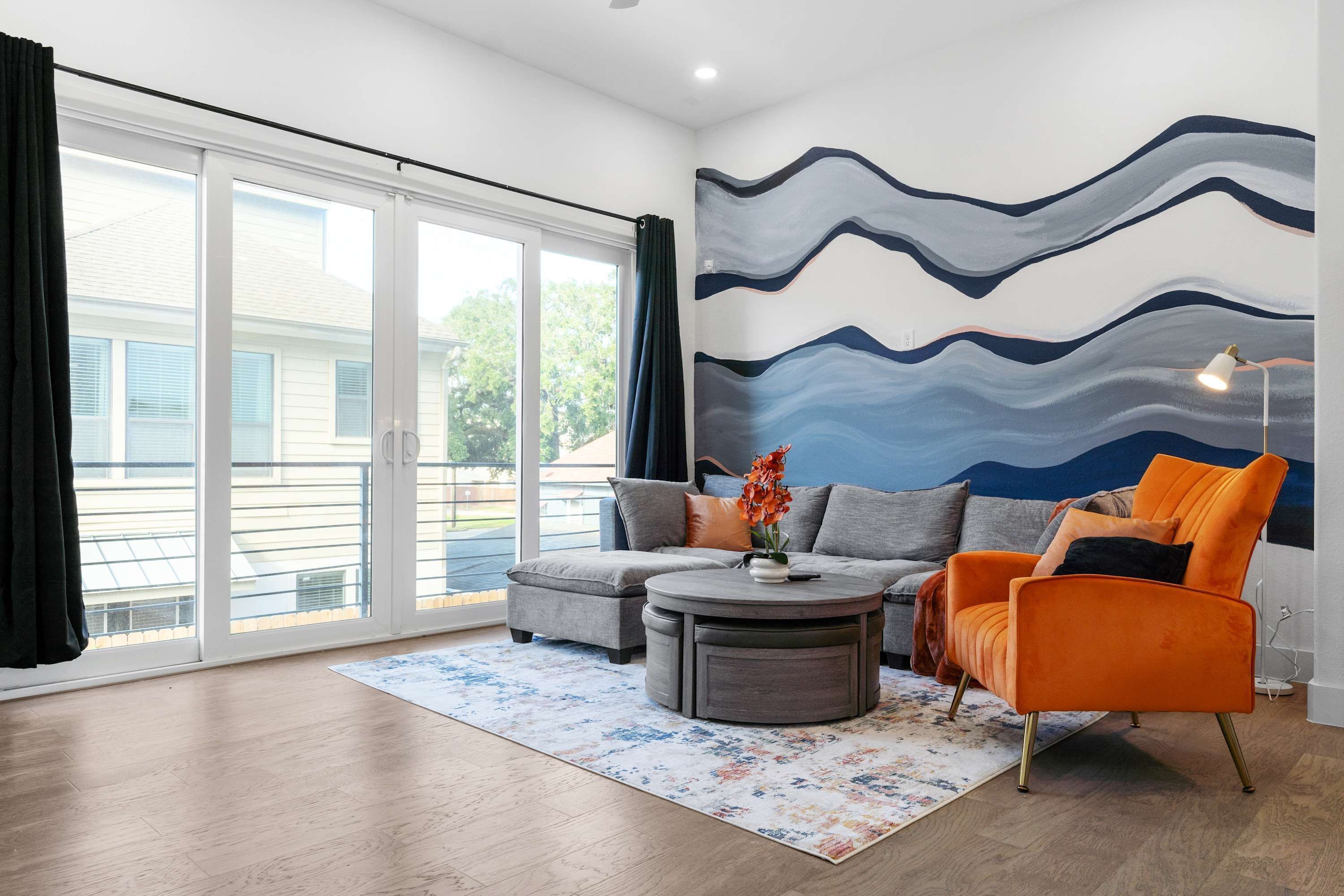 A modern living room with a grey sofa, an orange armchair, and a round coffee table.