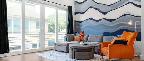 A modern living room with a grey sofa, an orange armchair, and a round coffee table.