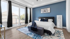 Un dormitorio con una cama grande, un ventilador de techo y vistas al exterior a través de un puertas corredera.