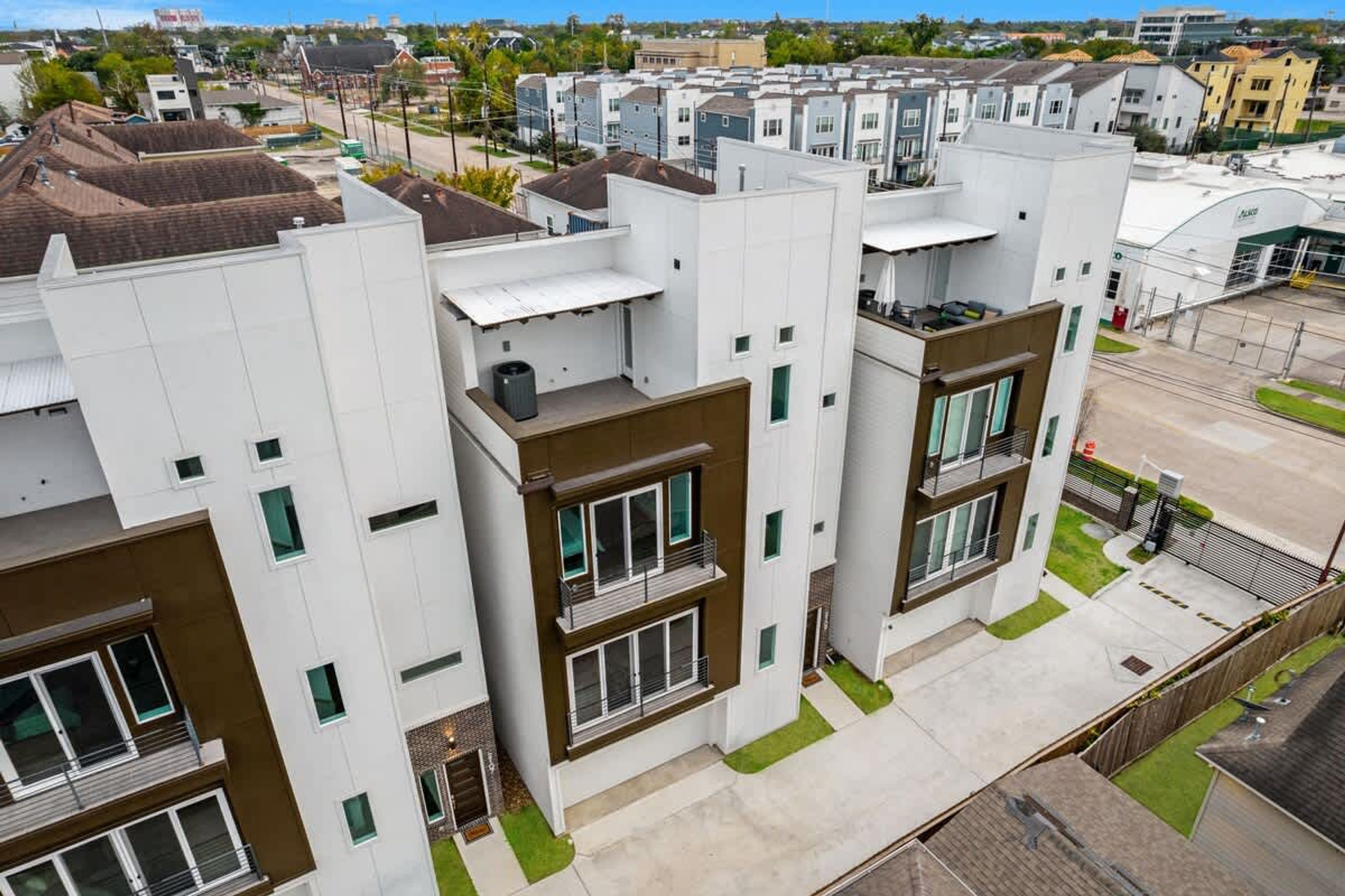 Un complejo moderno de apartamentos con varios edificios, cada uno con balcones y grandes ventanales.