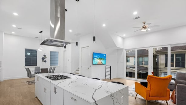 Una cocina moderna con una isla de mármol, un comedor con sillas y un amplio ventanal con vistas.