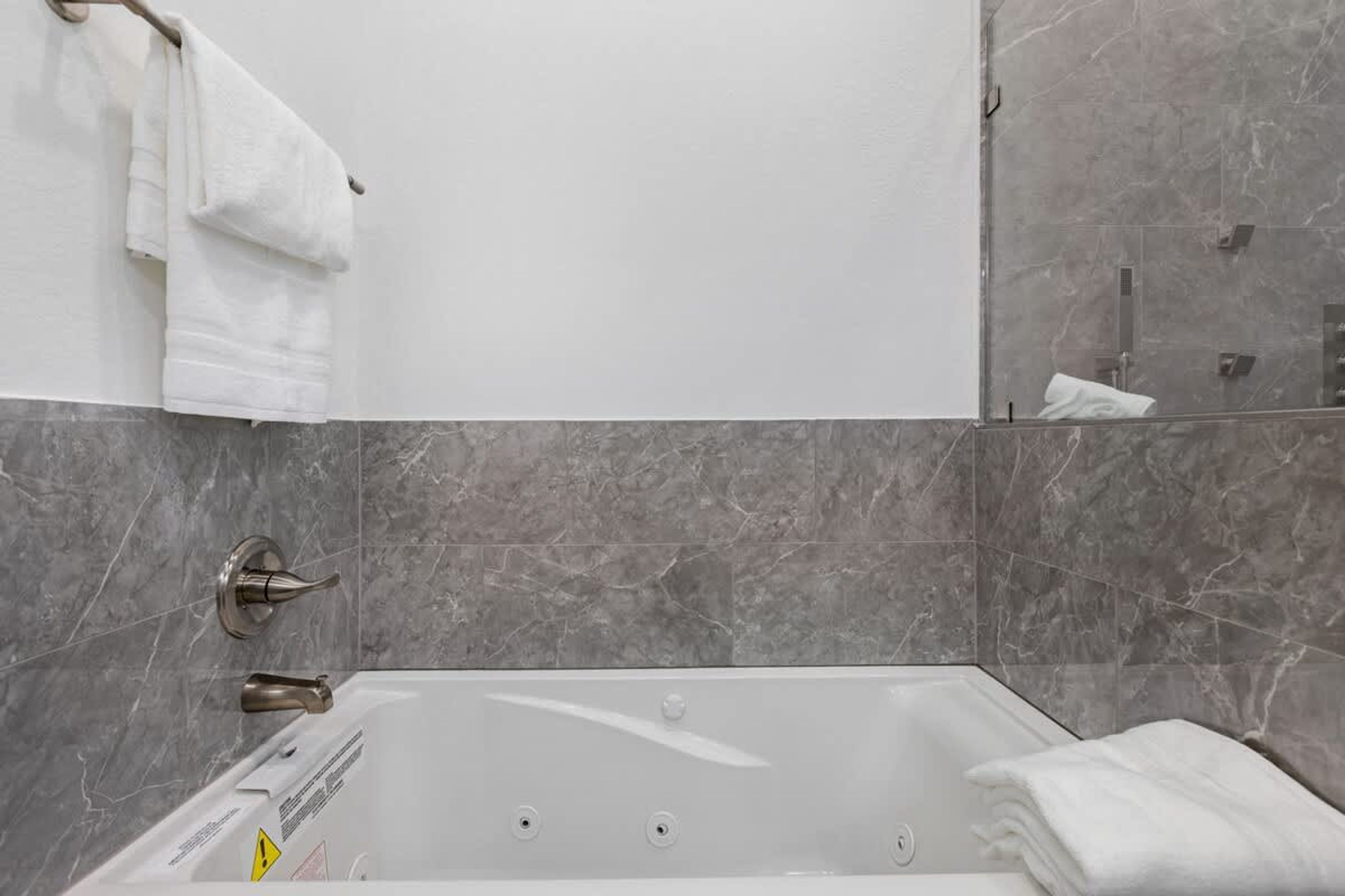 Un baño moderno con bañera, baldosas de mármol y un perchero para toallas.