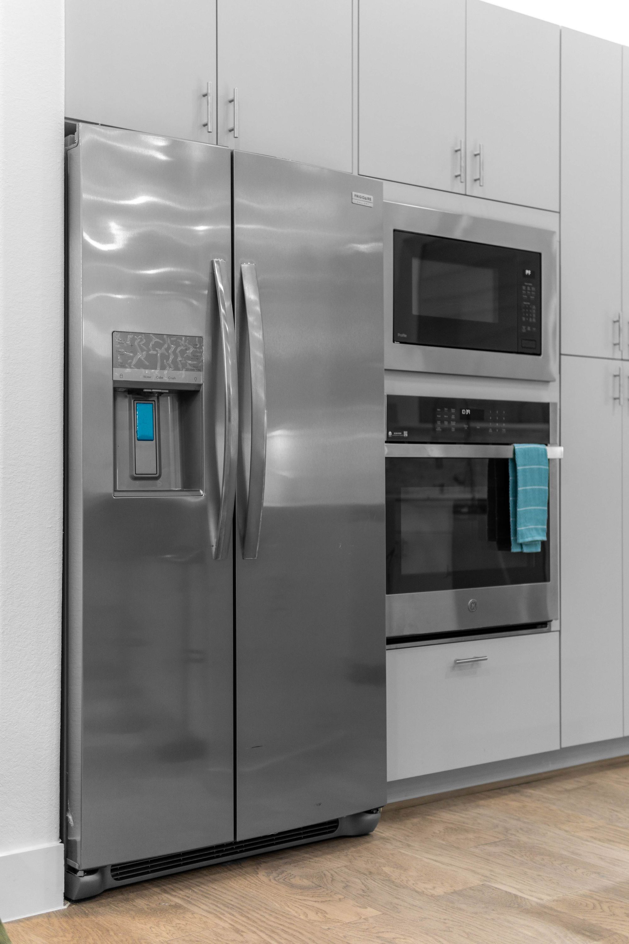 A stainless steel refrigerator with a water dispenser, a microwave, and an oven.